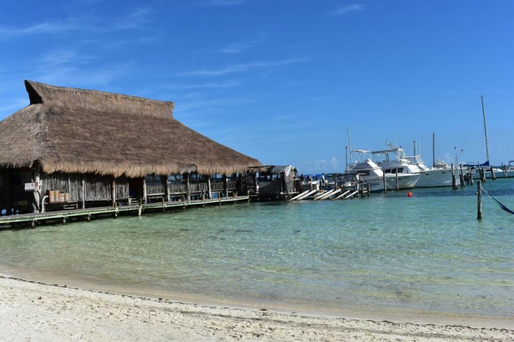 Playa Las Perlas en Cancún con arena blanca y palmeras junto al mar sereno.